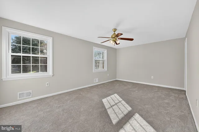 an empty room with windows and ceiling fan