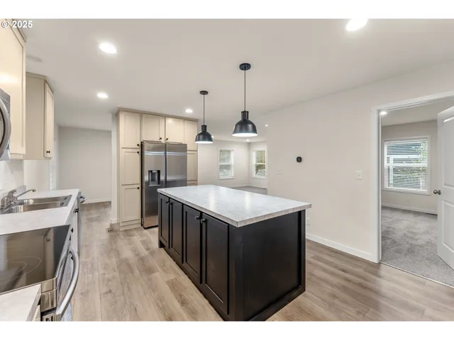 a kitchen with stainless steel appliances granite countertop a sink a stove and a wooden floors