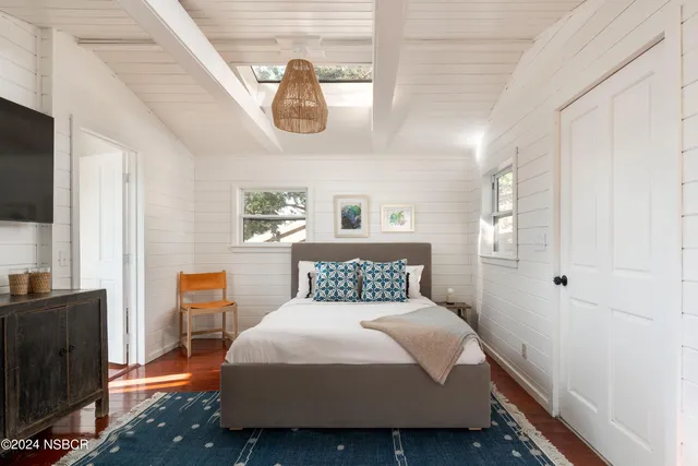 a bedroom with a large bed and a flat tv screen on dresser