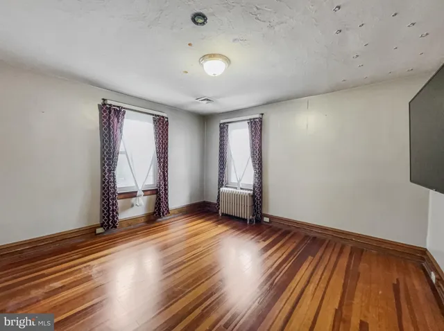 a view of an empty room with window wooden floor and closet