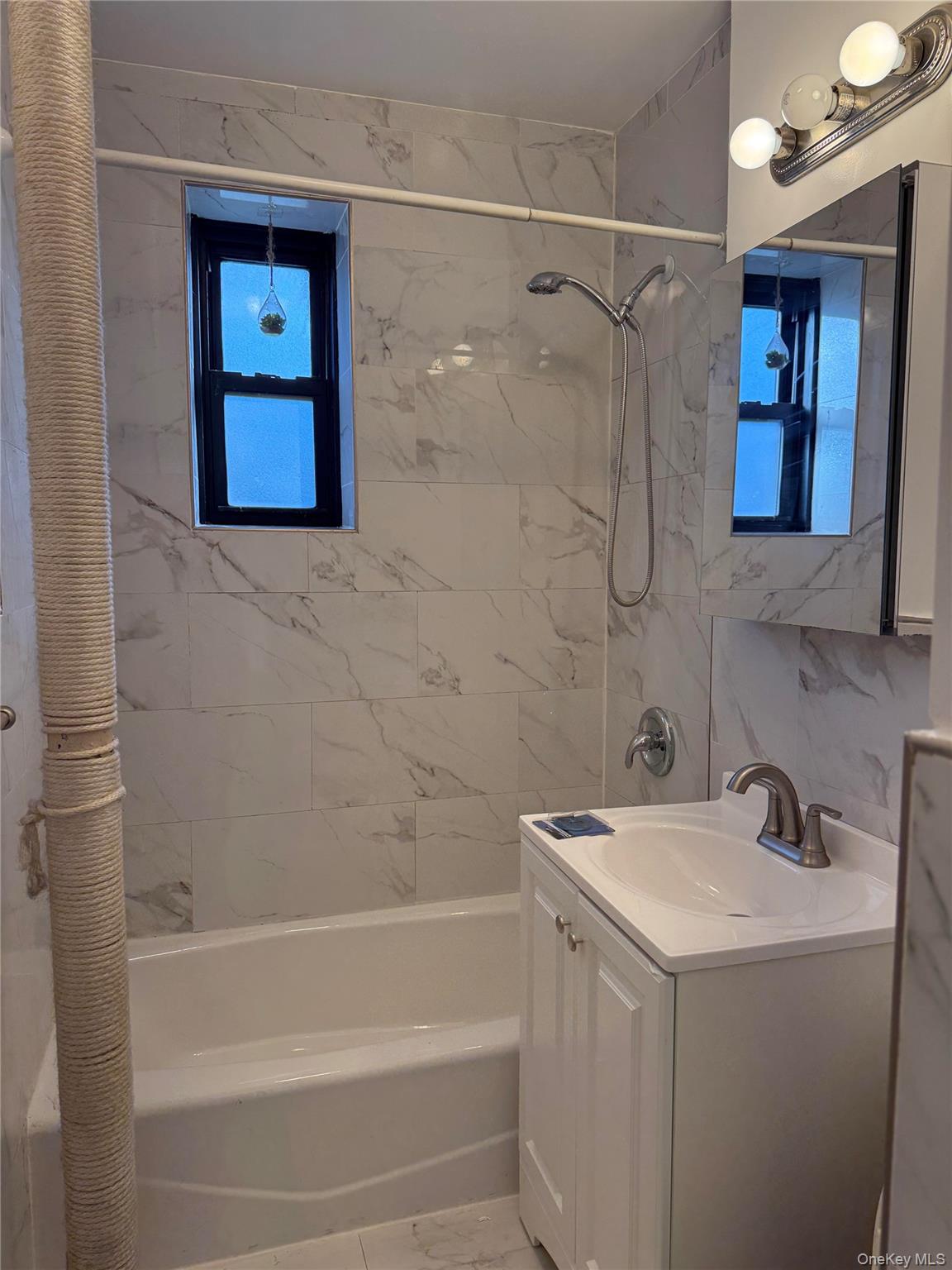 Bathroom featuring a white subway tile surround with subtle veining, complete with a white bathtub, and brushed nickel shower fixtures
