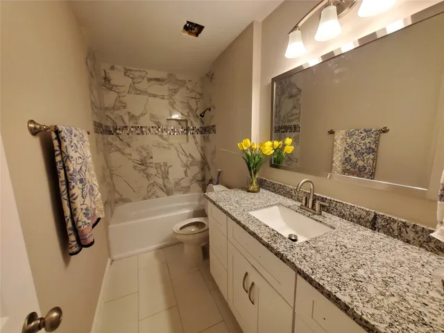 a bathroom with a granite countertop sink a toilet and bathtub