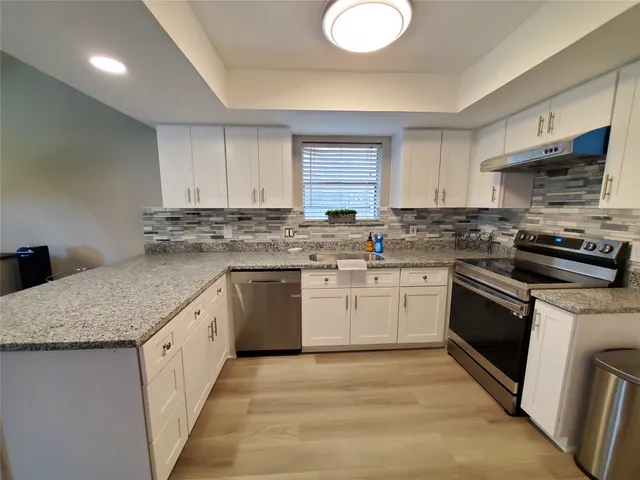a kitchen with granite countertop a sink stainless steel appliances and cabinets