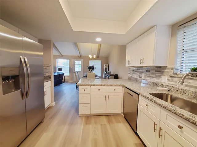 a kitchen with stainless steel appliances granite countertop a refrigerator sink and white cabinets