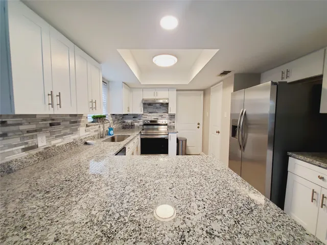 a kitchen with stainless steel appliances granite countertop a refrigerator a stove and a sink