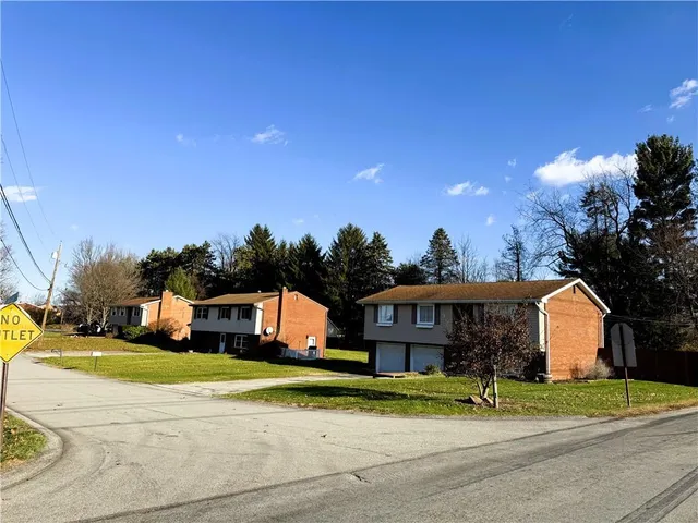 a front view of a house with a yard and trees