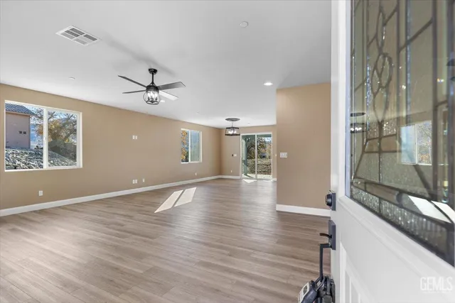 a view of an empty room with a window and wooden floor
