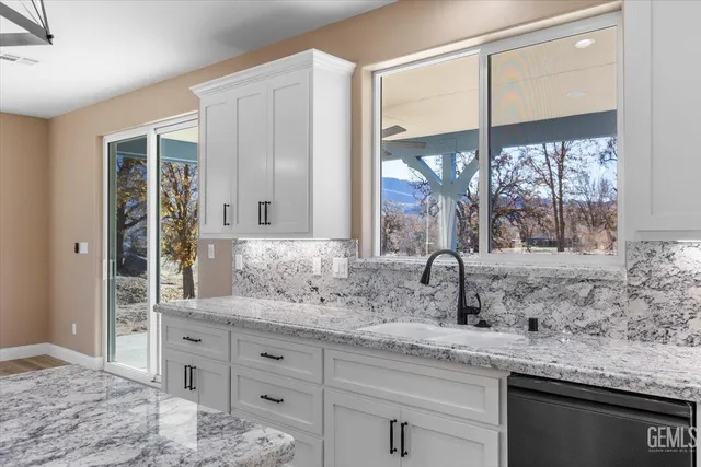 a bathroom with a granite countertop sink mirror and window