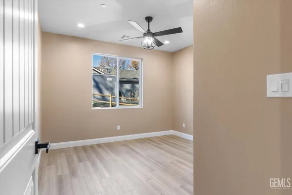 an empty room with wooden floor chandelier fan and windows