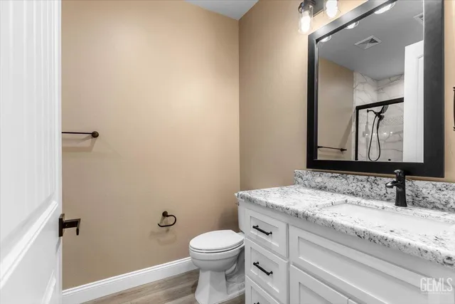 a bathroom with a granite countertop toilet sink and mirror