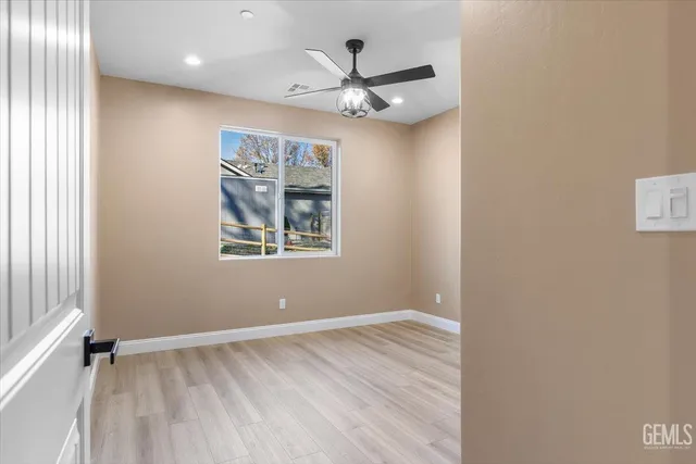 an empty room with wooden floor chandelier fan and windows