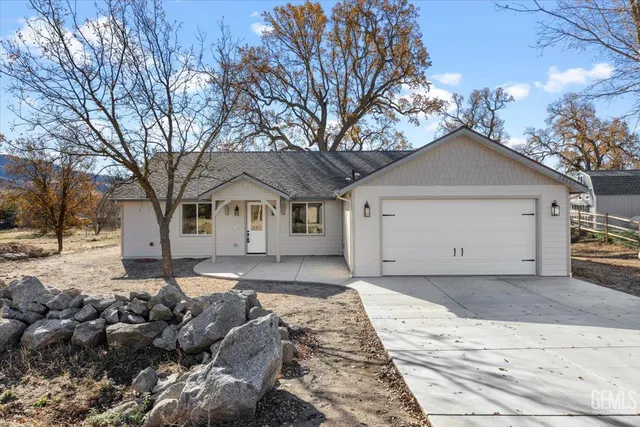 a front view of a house with a yard and large tree