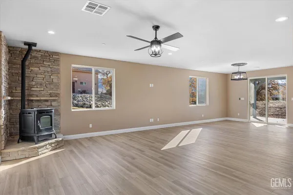 an empty room with wooden floor fireplace and windows
