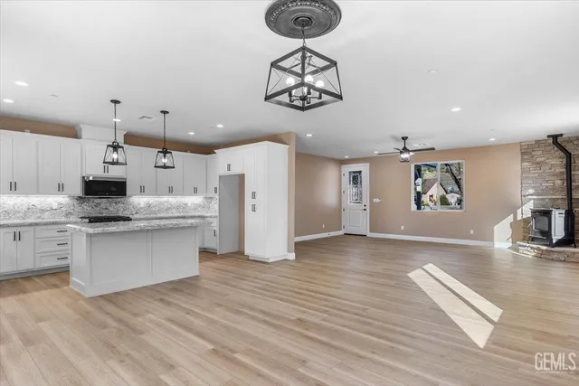 a kitchen with stainless steel appliances granite countertop a refrigerator a stove and white cabinets with wooden floor