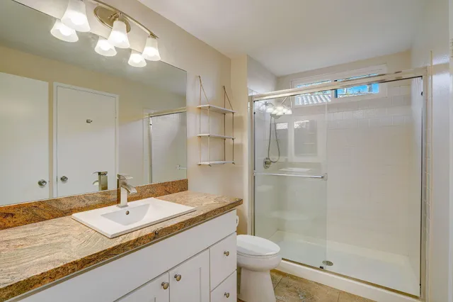 a bathroom with a granite countertop sink a toilet and shower