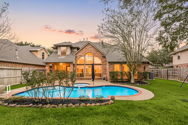 a view of a house with a yard and table and chairs under an umbrella