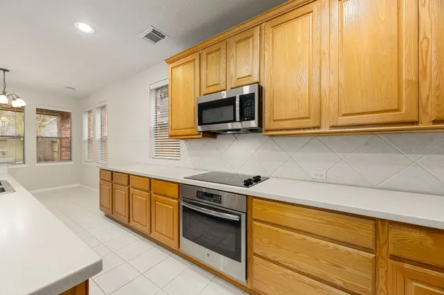 a kitchen with stainless steel appliances granite countertop white cabinets sink and a microwave