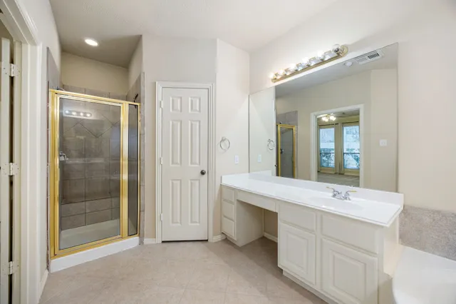 a spacious bathroom with a shower a sink and mirror