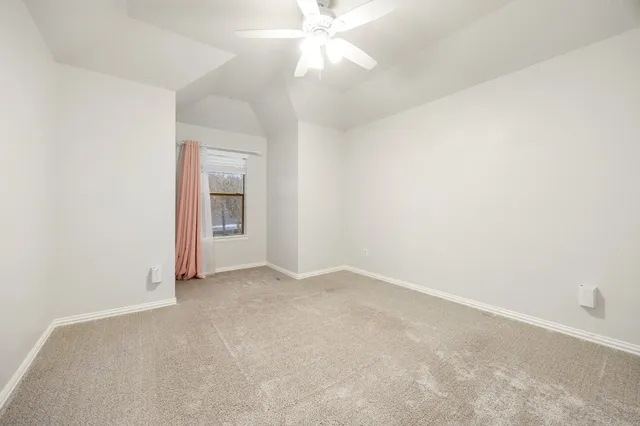 an empty room with a ceiling fan and a window
