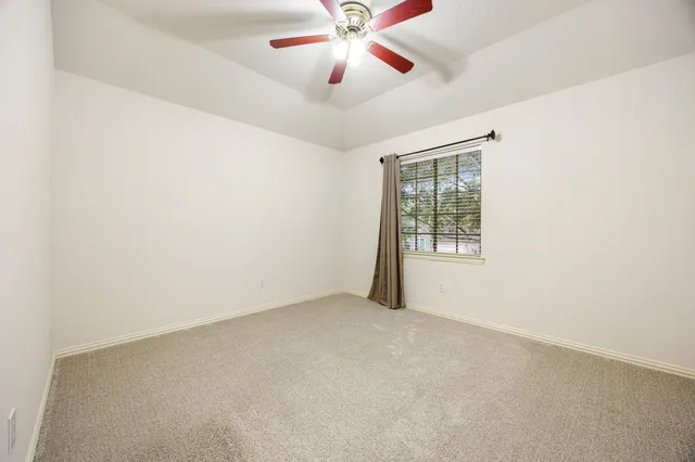 an empty room with chandelier fan and windows