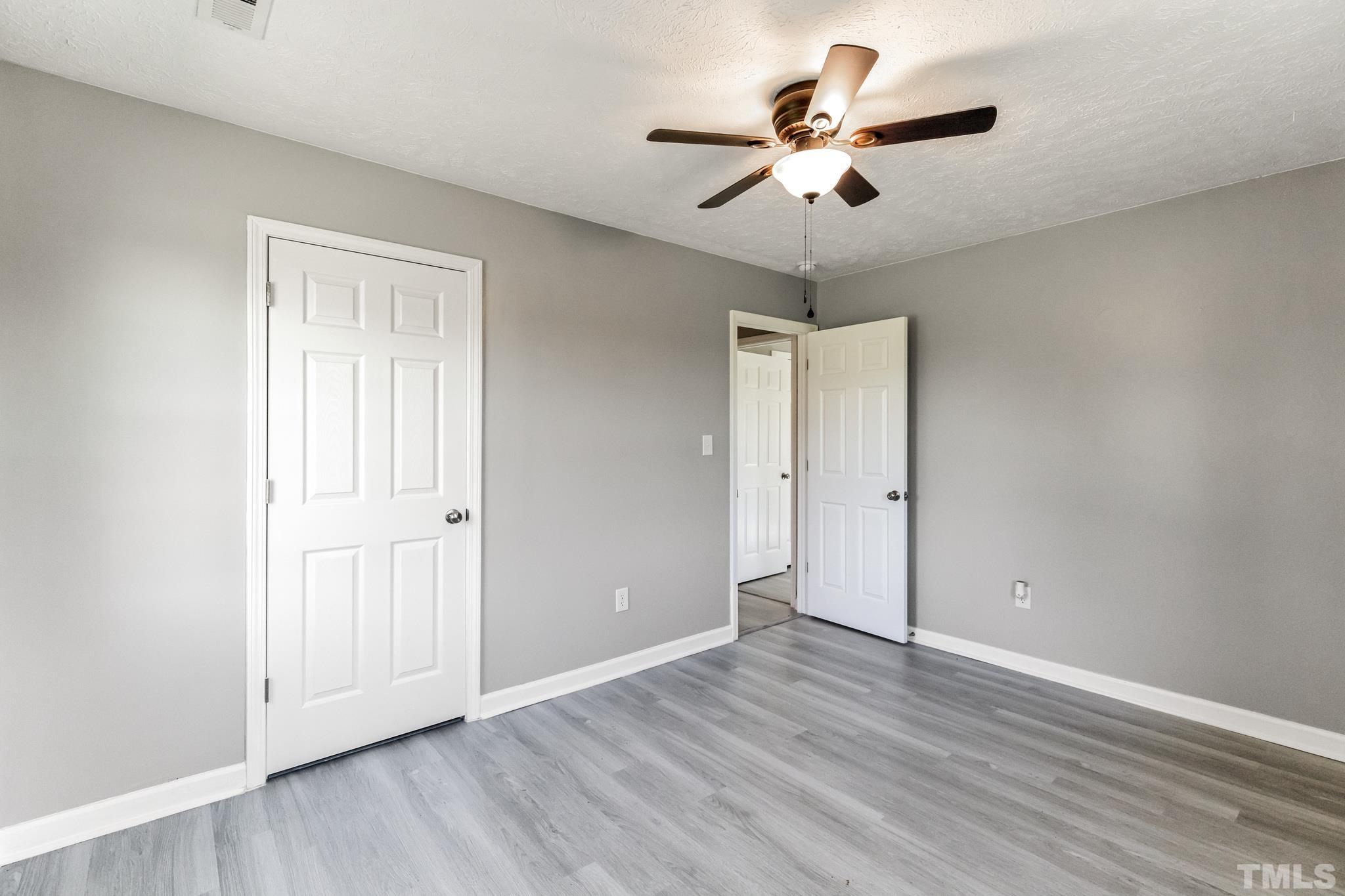 3763 Waycross Road Magnolia, NC 28453 - Photo 12 of 34 an empty room with wooden floor ceiling fan and windows