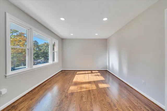 an empty room with wooden floor and window