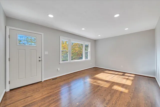 a view of an empty room with wooden floor and a window