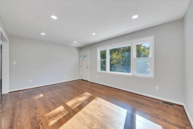 a view of an empty room with wooden floor and a window