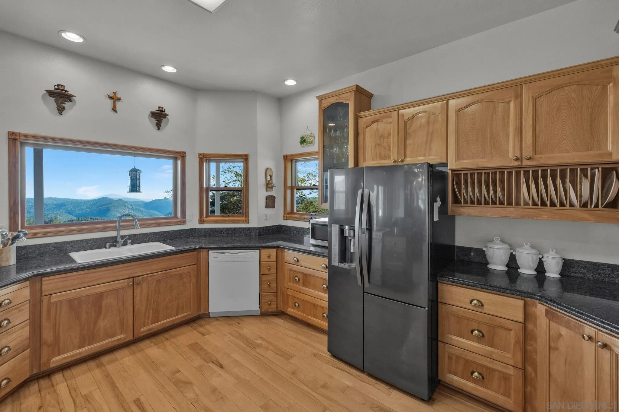 4819 Pine Ridge Avenue Julian, CA 92036 - Photo 13 of 51 a kitchen with stainless steel appliances granite countertop a refrigerator a sink dishwasher and wooden cabinets with wooden floor