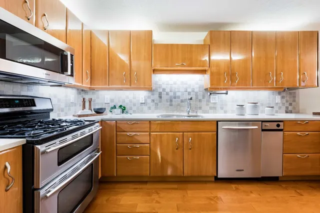 a kitchen with granite countertop wooden cabinets stainless steel appliances and a sink
