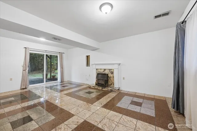 a view of an empty room with a fireplace and a window