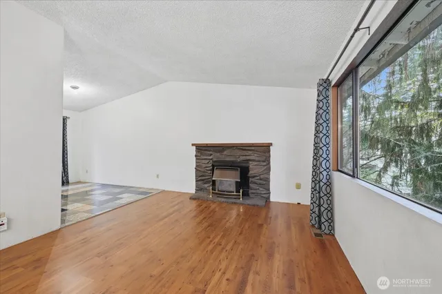 a view of empty room with wooden floor and fireplace