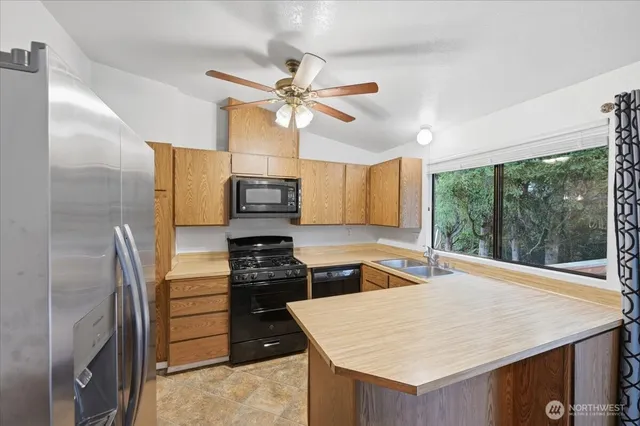 a kitchen with stainless steel appliances kitchen island granite countertop a refrigerator a stove and white cabinets with wooden floor