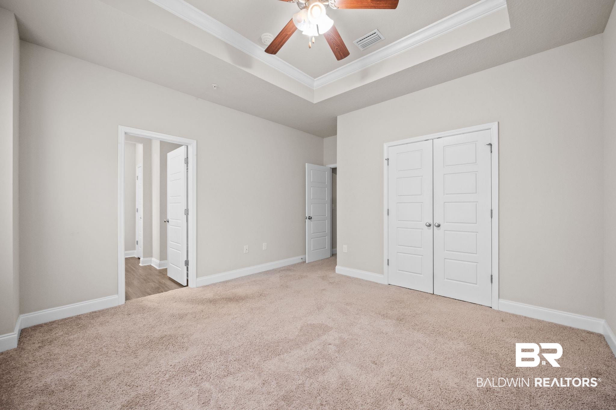6903 Spaniel Drive, Unit B Spanish Fort, AL 36527 - Photo 12 of 28 Unfurnished bedroom with carpet floors, a tray ceiling, visible vents, and crown molding