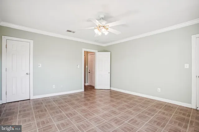 a view of an empty room with window and chandelier fan