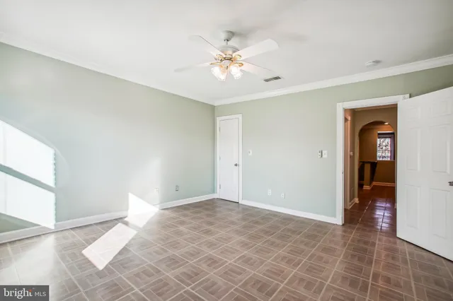 a view of an empty room with window and chandelier fan