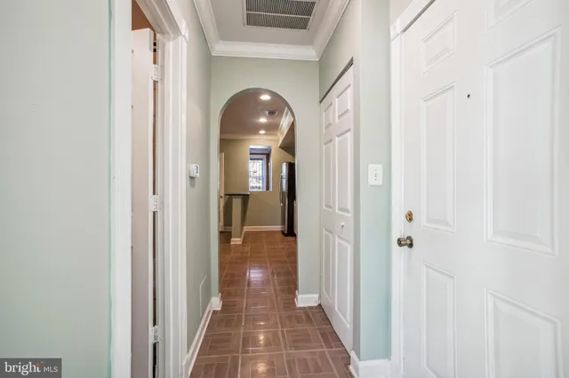 a view of a hallway with wooden floor and a bathroom