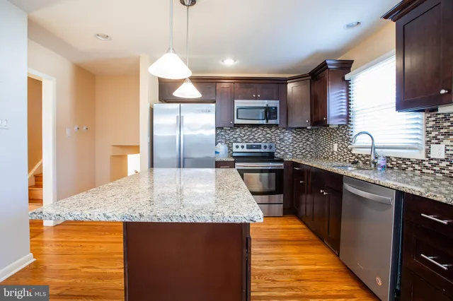 a kitchen with stainless steel appliances granite countertop a sink a stove and a wooden cabinets