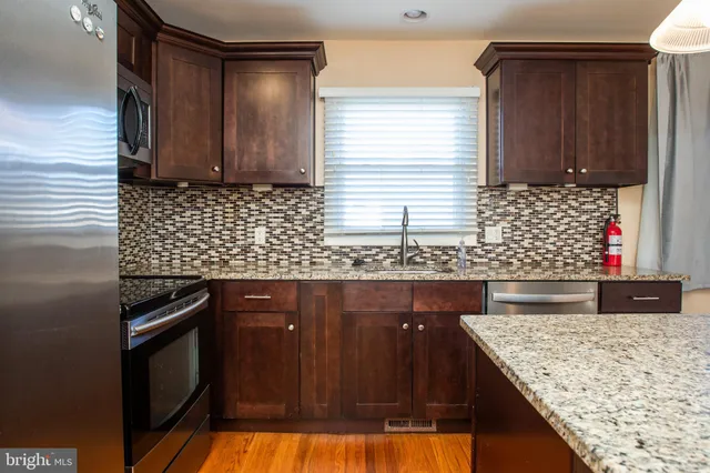 a kitchen with granite countertop wooden cabinets and a stove top oven