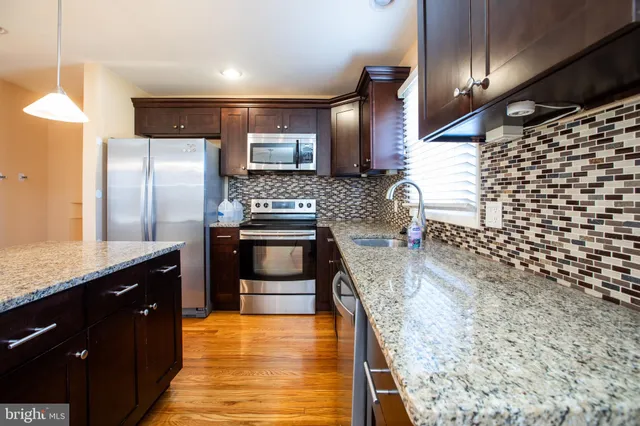a kitchen with stainless steel appliances kitchen island granite countertop a stove a sink and a refrigerator