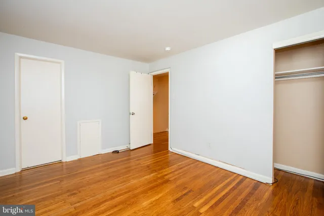 a view of an empty room with wooden floor and closet