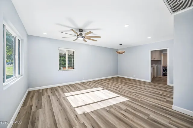 a view of empty room with wooden floor and fan