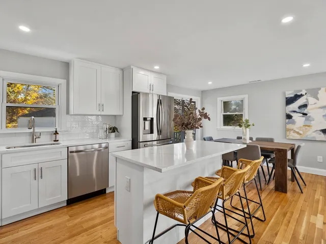 a dining hall with stainless steel appliances kitchen island granite countertop a dining table chairs and granite counter tops