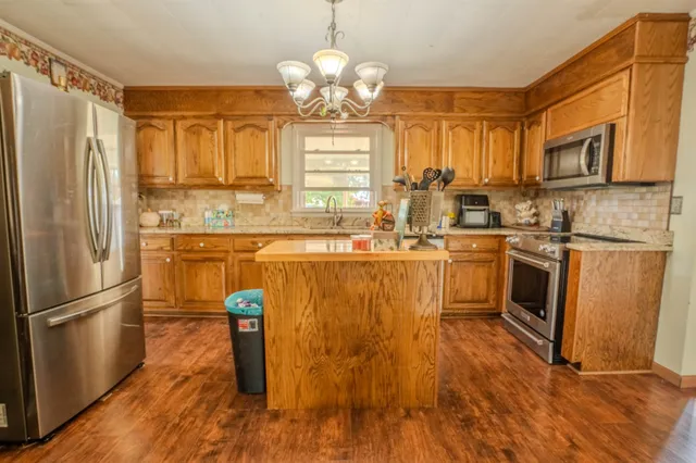 a kitchen with stainless steel appliances granite countertop a sink a stove and refrigerator