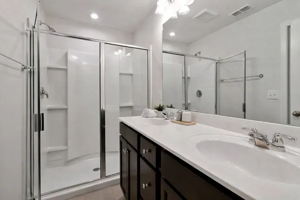 a bathroom with a double vanity sink mirror and shower
