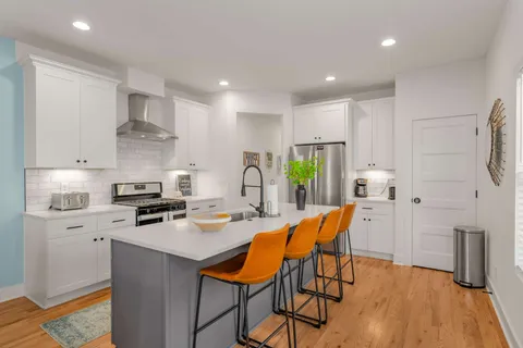 a kitchen with stainless steel appliances granite countertop a stove refrigerator a sink dishwasher and a stove with wooden floor