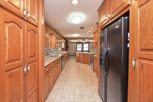 a large kitchen with stainless steel appliances granite countertop a refrigerator and a stove
