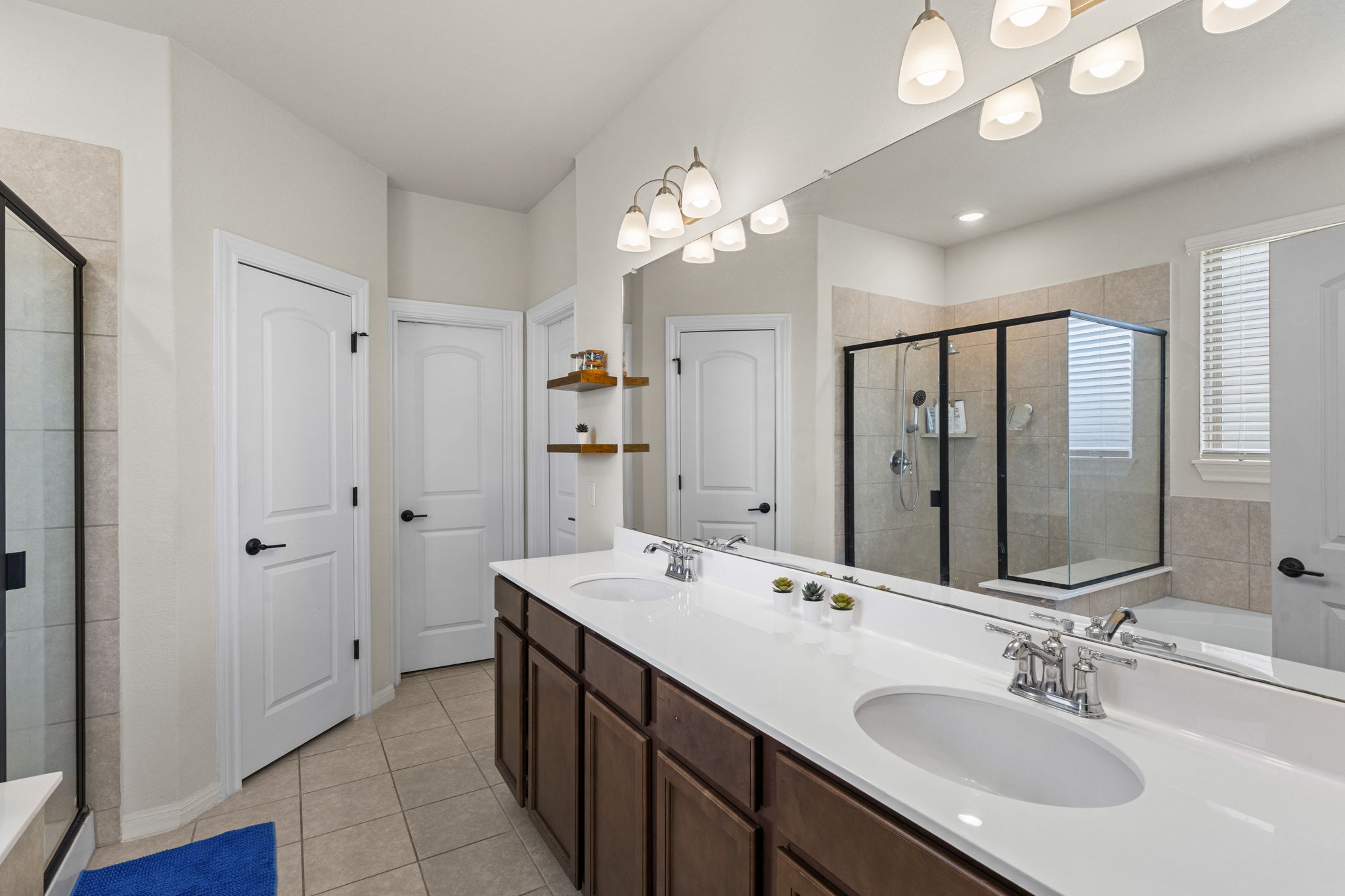 548 Purple Heart Drive Buda, TX 78610 - Photo 15 of 35 Dual vanities with pristine white counters and a spacious glass-enclosed shower highlight this tranquil primary bathroom.