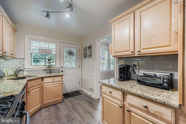 a kitchen with granite countertop a sink stainless steel appliances and cabinets