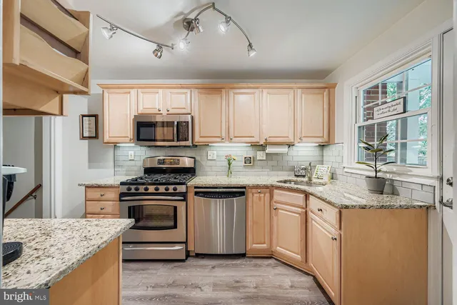 a kitchen with kitchen island granite countertop a stove sink microwave and refrigerator